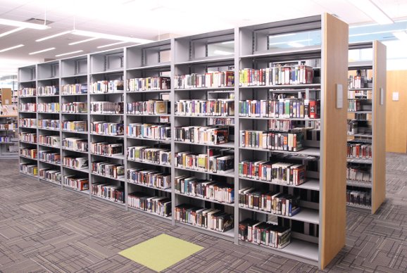 K-12 or academic library stacks with wood end panels — open student-accessible shelving