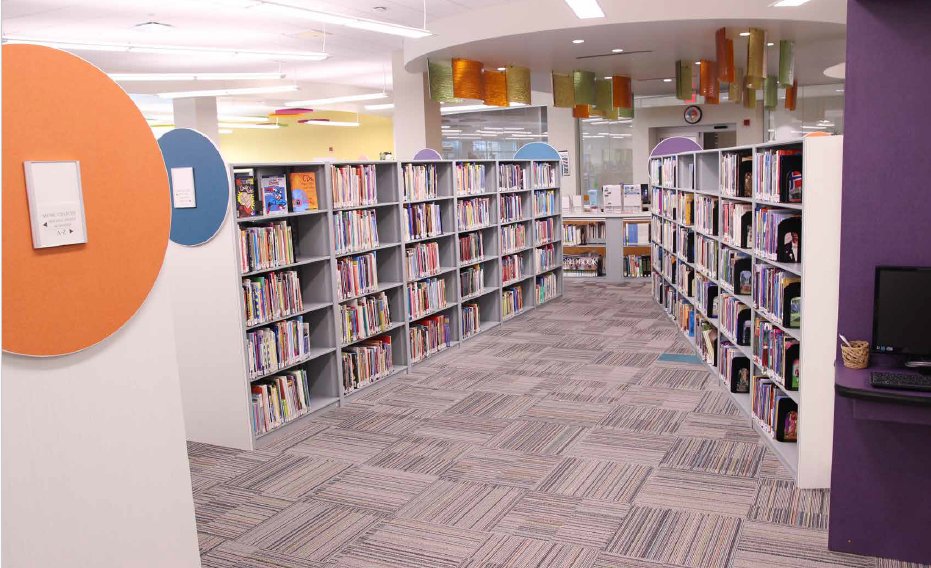 K-12 library stacks with colorful book displays and patterned carpet