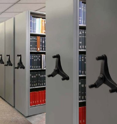 Law library high-density mobile shelving with handwheel detail and red-bound volumes