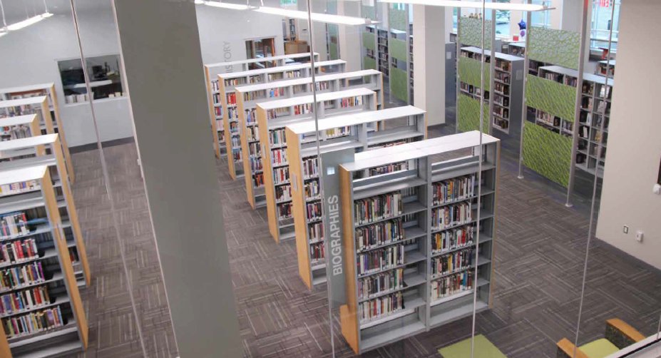 Open library stacks photographed from above — wood end panels, biographies section